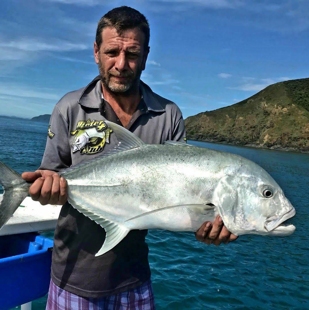 A giant trevally held up on the boat