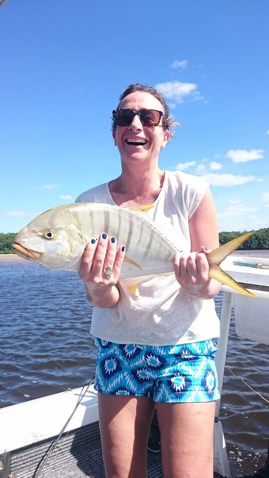 A laughing angler holding a golden trevally